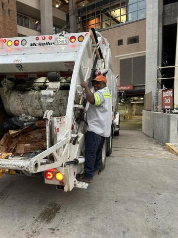 Quincy Styles, an SWR worker, rides on a trash truck heading under DKR-Texas Memorial Stadium after a home football game