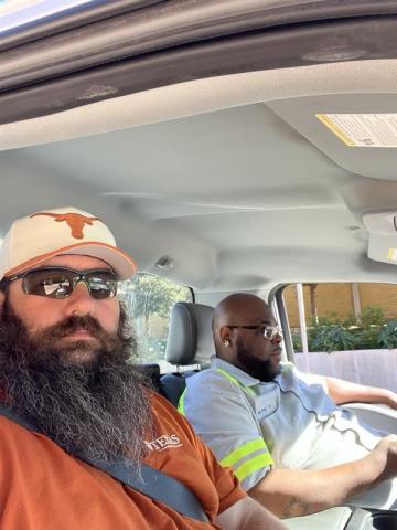 Jeff Alford (left), SWR supervisor, and Milton Roberson Jr., SWR team lead, wait in a pickup truck for the next trash valet load during a home football game. They haul trash and recycling from the stadium to roll-off dumpsters on Red River Street, hand-sorting the bags to ensure materials are properly separated.